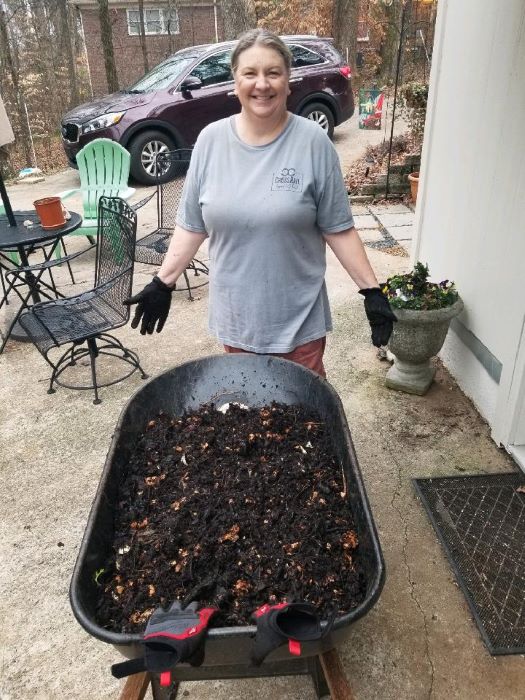 Woman poses with wheelbarrow of finished compost