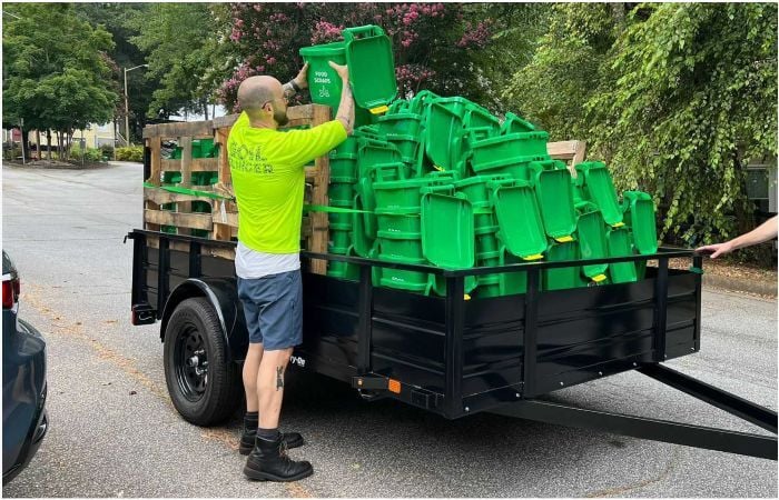 a CompostNow employee loading food scrap bins into a trailer